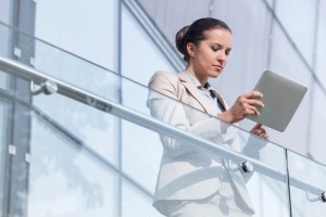 Beautiful young businesswoman using digital tablet at office railing